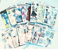 Photo showing 15 vintage sewing pattern packets laid out, featuring various baby, toddler, and doll clothing patterns from Simplicity, McCall's, and Daisy Kingdom.