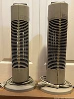 Front view of two Sharper Image Ionic Breeze air purifiers standing side by side, cords wrapped at base.