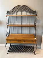Front view of the Ethan Allen baker's rack showing wrought iron frame with lattice top, wooden shelves and counter, and two drawers.