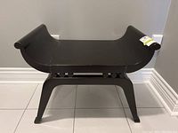 Front view of black wooden bench with curved seat showing surface wear.