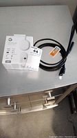 Google Chromecast with Google TV HD in original box next to black HDMI cable