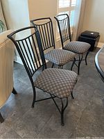 Group view of three black steel dining chairs with patterned gray upholstered seats.