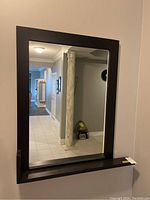 Straight-on front view showing the full mirror, frame, and integrated shelf.