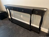 Front view of the dark wooden sofa table showing four ring-pull drawers and turned legs.