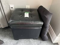 Storage stool with button-tufted vinyl lid and spare seat cushion beside it