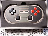 Close-up of the 8Bitdo NES30 PRO controller in the foam-lined tray inside the box, showing the button layout, dual analog sticks, and D-pad.