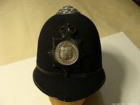 Front view of black felt police helmet with badge and chinstrap