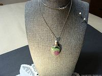 Full view of the necklace on a display bust, showing the pendant and chain.