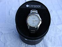 Full view of Citizen Eco-Drive watch in black Citizen branded display case showing the watch's face and metal band.