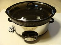 Photo of the Crock Pot slow cooker fully assembled, showing the black ceramic pot inside the stainless steel base with side handles and a glass lid with handle on top.