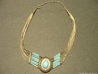 Full view of the native turquoise and sterling silver necklace laid flat on dark surface for detailed view of design, strands, and clasp