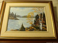 Frontal view of framed oil painting showing fall lakeside landscape with signature.