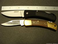 Two folding knives with a ruler for scale showing blade length and handle detail