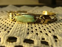 Close-up view of the turquoise stone set in silver bangle with decorative swirls and feathers.