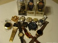 Full view of 13 watches with multiple bands and styles including metal, leather, and novelty Elvis watches in cases