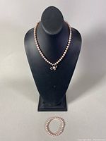 Photo showing the pearl necklace on a display bust and the stretch bracelet in front.