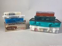 Stacked closed tackle boxes and bins showing containers included in lot