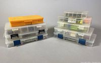 Multiple plastic storage bins stacked in two piles showing the variety of tackle boxes containing fishing accessories