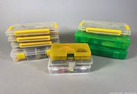 Image of six transparent yellow and clear plastic fishing tackle storage boxes and three green plastic storage bins arranged on a neutral surface.