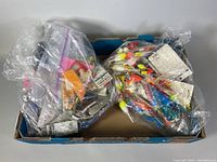 Two plastic bins containing multiple plastic bags filled with various fishing lures, floats, hooks, and other accessories arranged inside for storage and sorting.