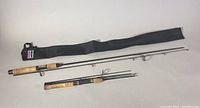 Two fishing rods laid out with black fabric carrying case.