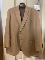 Full front view of camel jacket on hanger