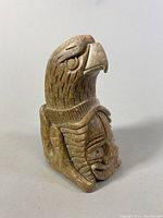 Front-right side view of carved soapstone eagle and face totem showing detailed feathers and eagle eye.