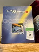 Front of original box labeled Zepter Bioptron Compact III showing device and accessories