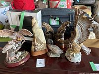 Photo showing the entire lot of bird and tiger figurines on a table, including Woodland Guardian owl sculpture, tigers, and other birds.