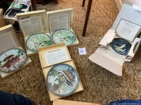 Five porcelain plates in original boxes with certificates displayed on carpet