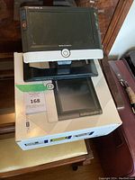 Digital reading magnifier device on adjustable stand placed on top of its original box on a wooden table.