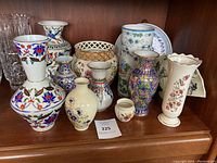 Front view of all vases and pottery pieces on wooden shelf showing arrangement and detail