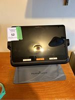 Front view of Humanware monitor on adjustable stand showing screen, control buttons, and base