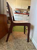 Side profile of a chair showing dark wood frame and angled back leg
