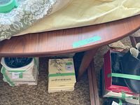 Partial top view of oval tabletop under protective covering with green tape label