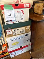 Stack of shoe boxes from various brands including Rieker, Clarks, Dr. Scholl's showing size 10 labels