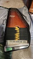 Full-length view of autoharp showing overall body shape, sunburst wood finish, chord bar assembly