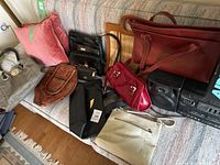 Photo showing all leather purses and wallets including grey handbag, brown purse, red JOOP tote, red purse, beige crossbody, and two black wallets.