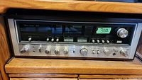 Front view of stereo receiver showing silver faceplate, tuning window and control knobs