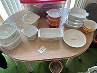 Overview of multiple Pyrex and Corningware dishes arranged on a table showing variety of sizes and shapes with blue cornflower patterns mostly visible