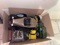 Box containing vintage car decanter, a green and yellow toy cars, wooden mantel clock, decorative plate, glass vase, and wood box with playing cards.