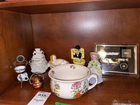 Overview of lot showing figures, chamber pot, frog light, small kettle, and framed steampunk art.