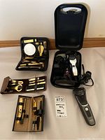 Image showing all three travel manicure kits with their tools, Wahl electric hair clipper with guards inside carrying case, and Philips Series 3000 shaver out of case.