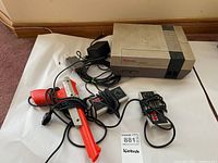 Full lot showing Nintendo NES console, two controllers, Zapper light gun, power adapter, and cables on a white sheet