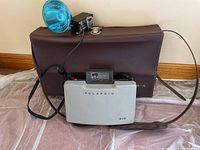 Polaroid 315 camera with attached flash, brown carrying case visible in background.