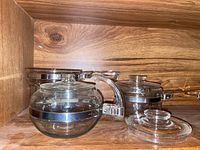 Clear glass Pyrex teapot and pots with metal bands and lids.