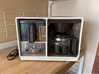 Front view of vintage cream colored General Electric Spacemaker coffee maker with glass carafe and timer panel.