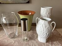 Five vases and one oil sprayer arranged on a table shown together to provide overall view