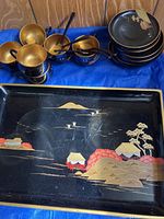 Full set showing tray, tea cups, and plates arranged on blue cloth.