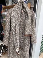 Front view of the textured multi-tone brown/cream ladies winter coat with matching scarf hanging on a wooden hanger.